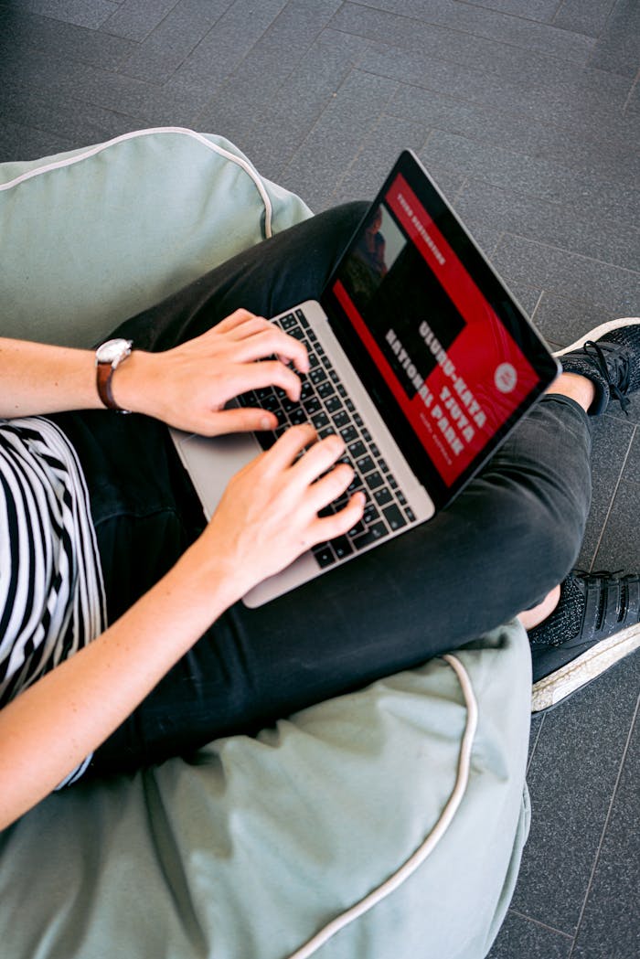 services-04 Person working remotely on a laptop while sitting comfortably on a beanbag chair indoors.